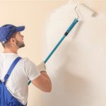 Interior house painter with a roller and overalls and a hat on